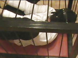 Rigidcuffed slave in a cage