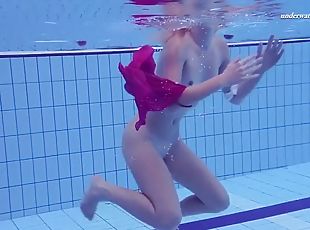 Playful blonde girl swims naked in olympic swimming pool