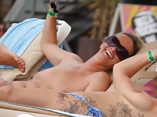 Tattooed girl and her topless friend tanning topless